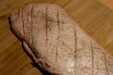 The fatty skin of the duck breast scored in a crosshatch pattern